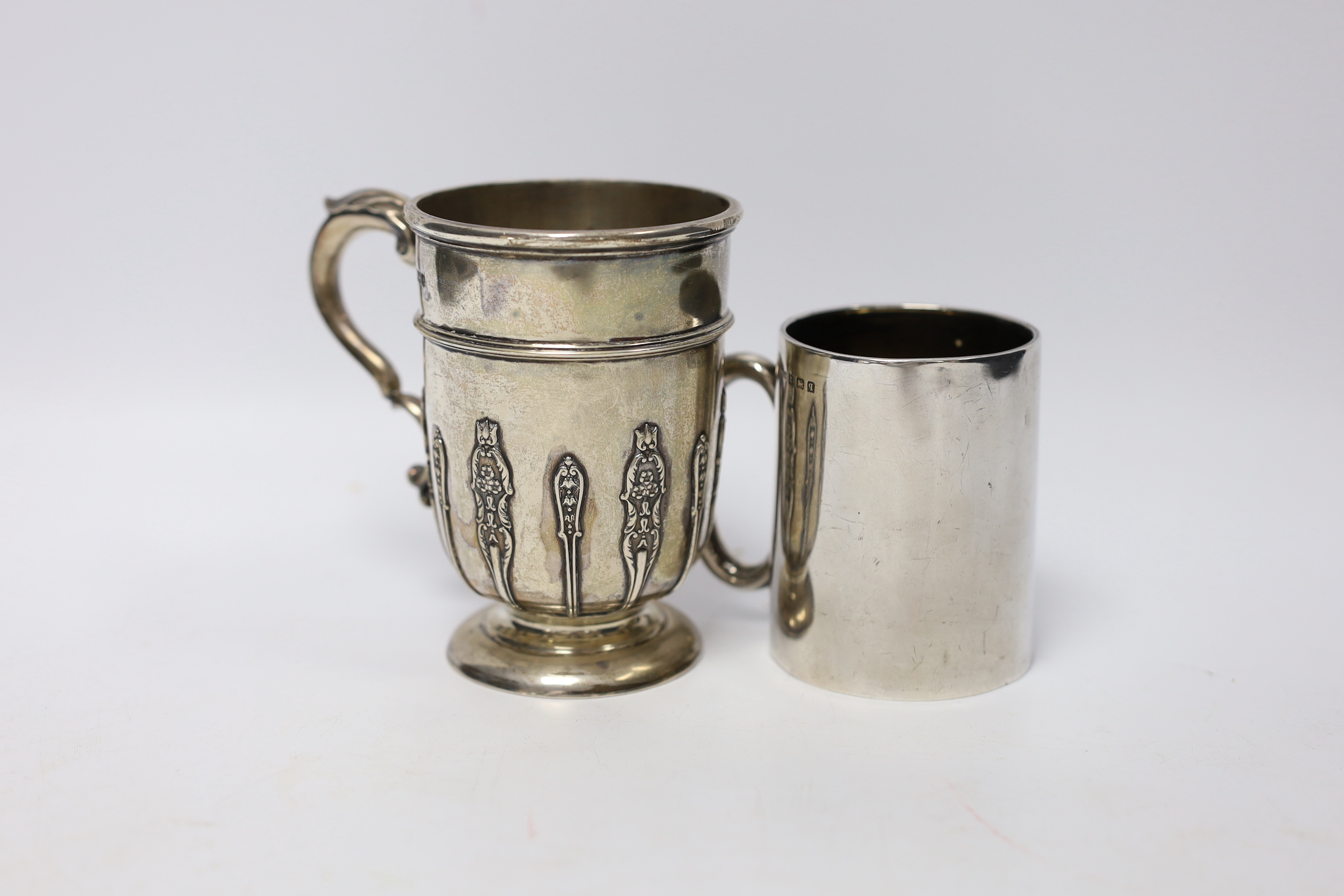 A George V silver christening mug, with card cut decoration, Sibray, Hall & Co, Sheffield, 1922, height 10.1cm and one other smaller George V silver christening mug, 8.7oz.